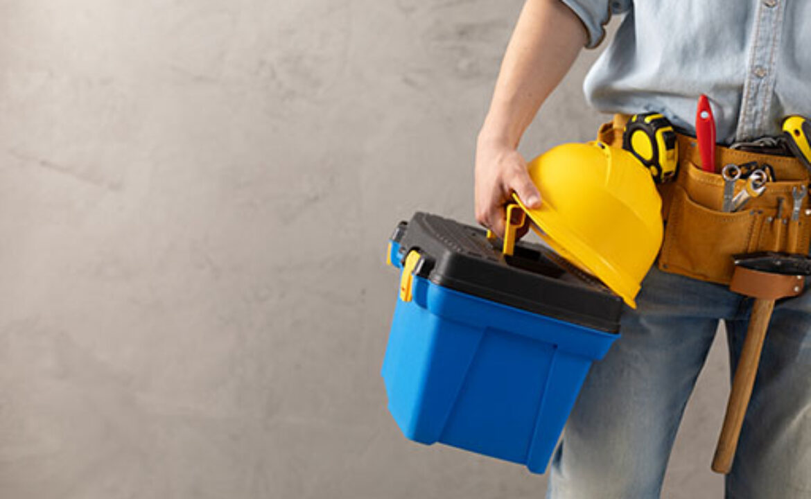 Worker man holding construction helmet tool and toolbox near con