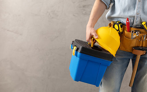 Worker man holding construction helmet tool and toolbox near con