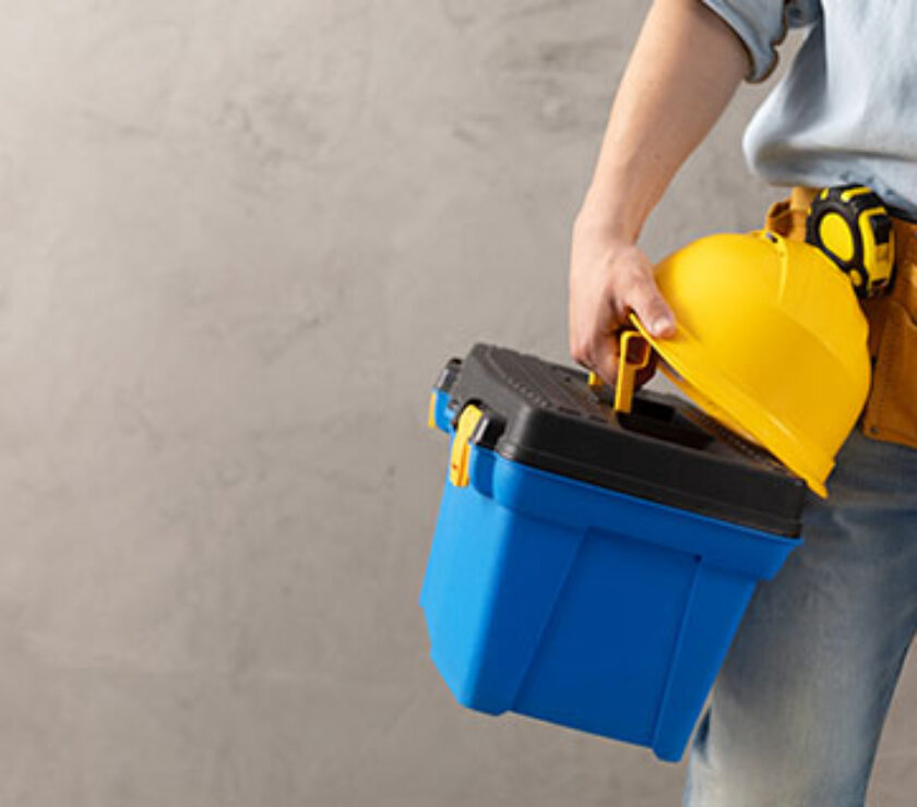 Worker man holding construction helmet tool and toolbox near con